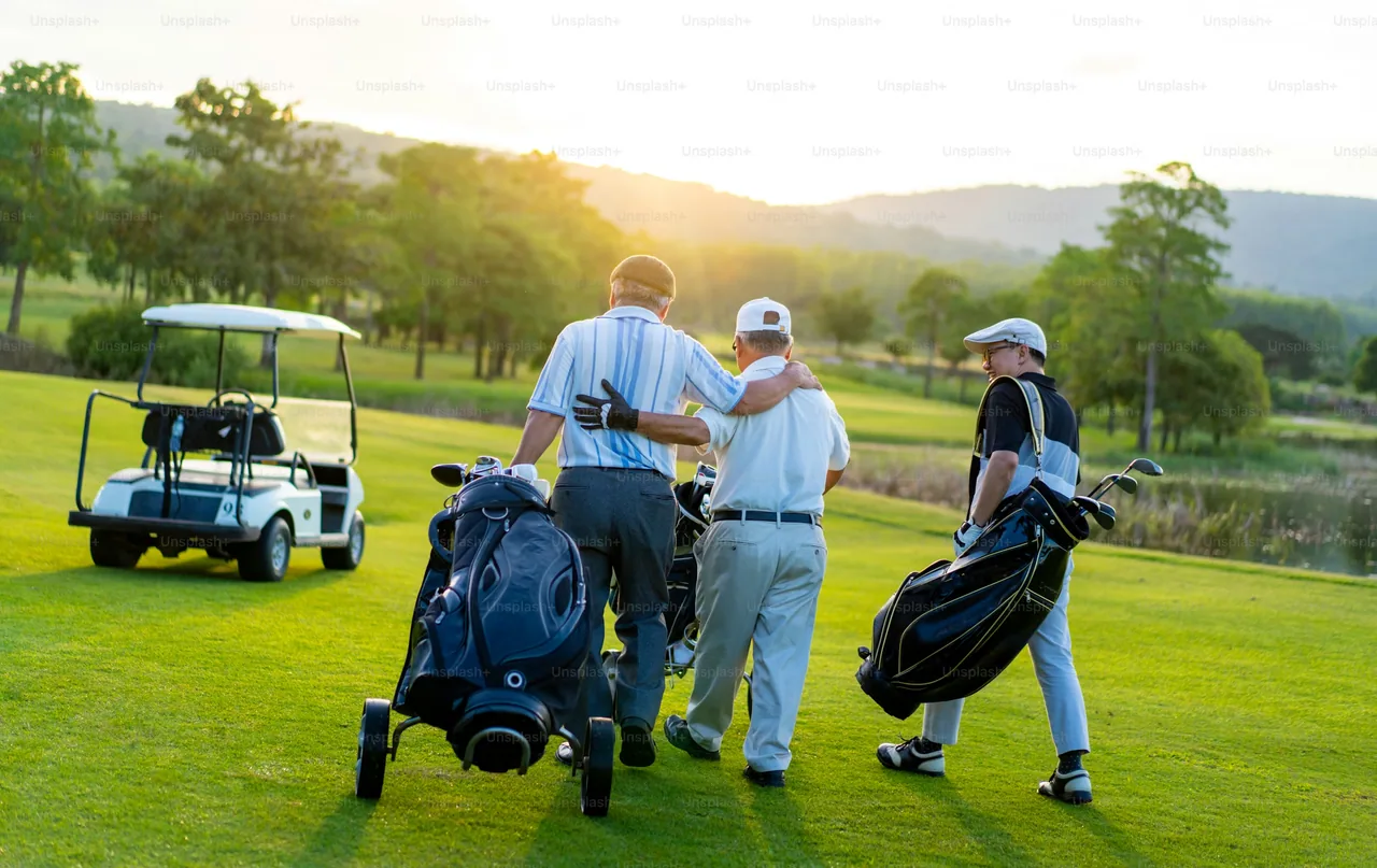 Golfers walking together on a course at sunset.